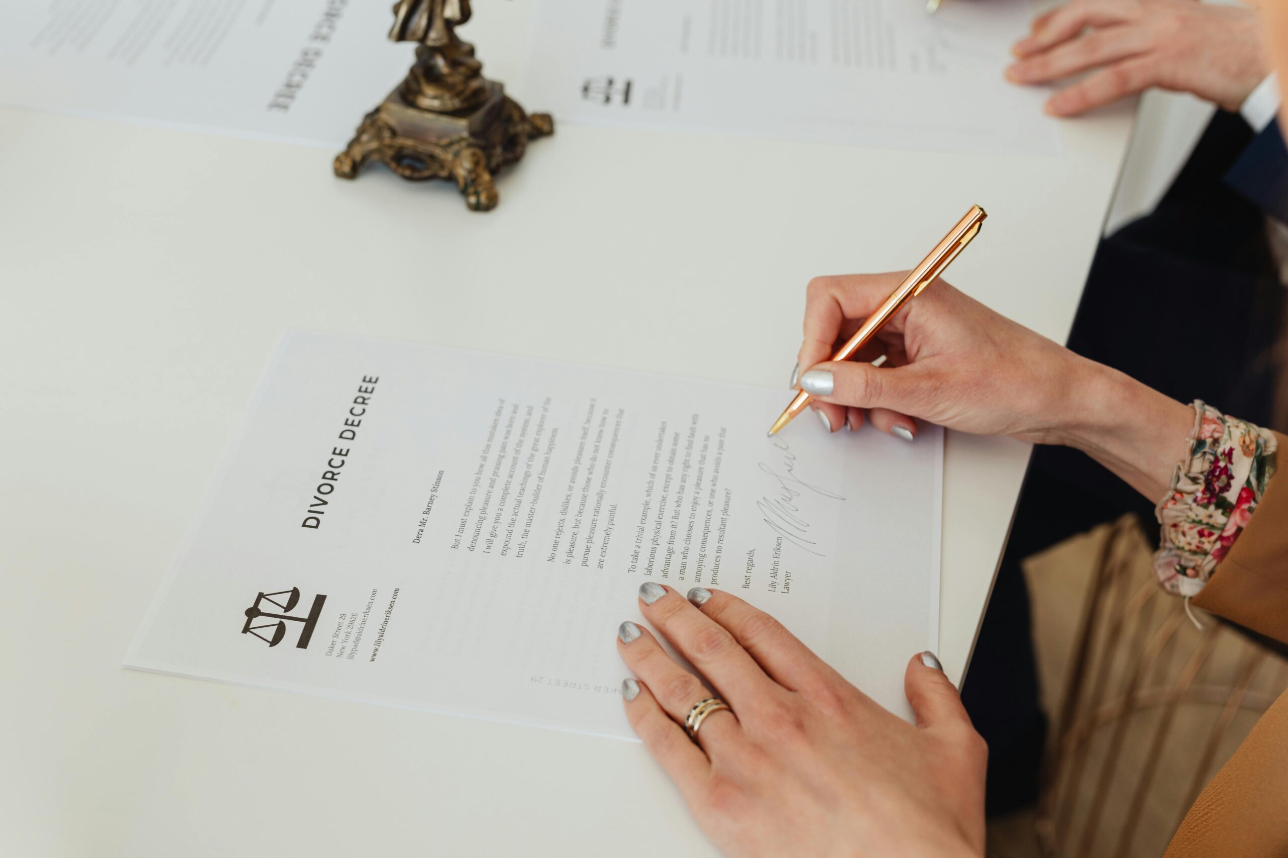 Close-up of hands signing a divorce decree document on a desk, showcasing legal process.